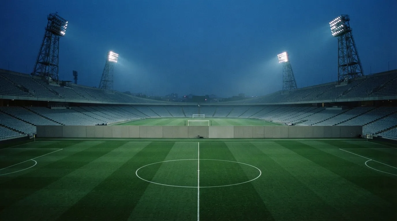 Een leeg voetbalstadion met lichtmasten bij schemering