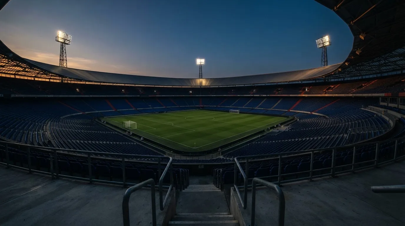 Een leeg voetbalstadion met lichtmasten bij schemering
