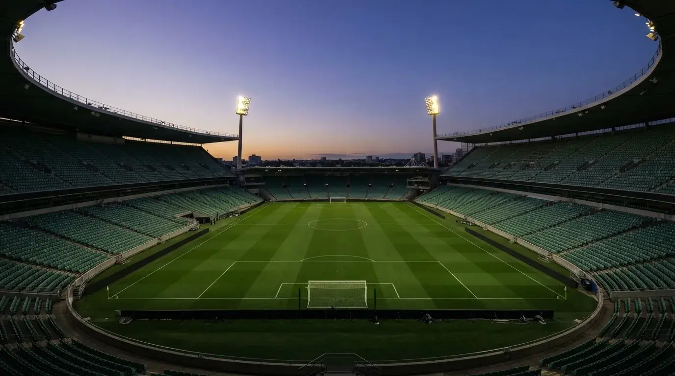 Een leeg voetbalstadion met lichtmasten bij schemering