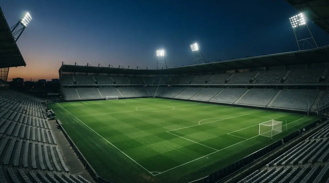 Een leeg voetbalstadion met lichtmasten bij schemering