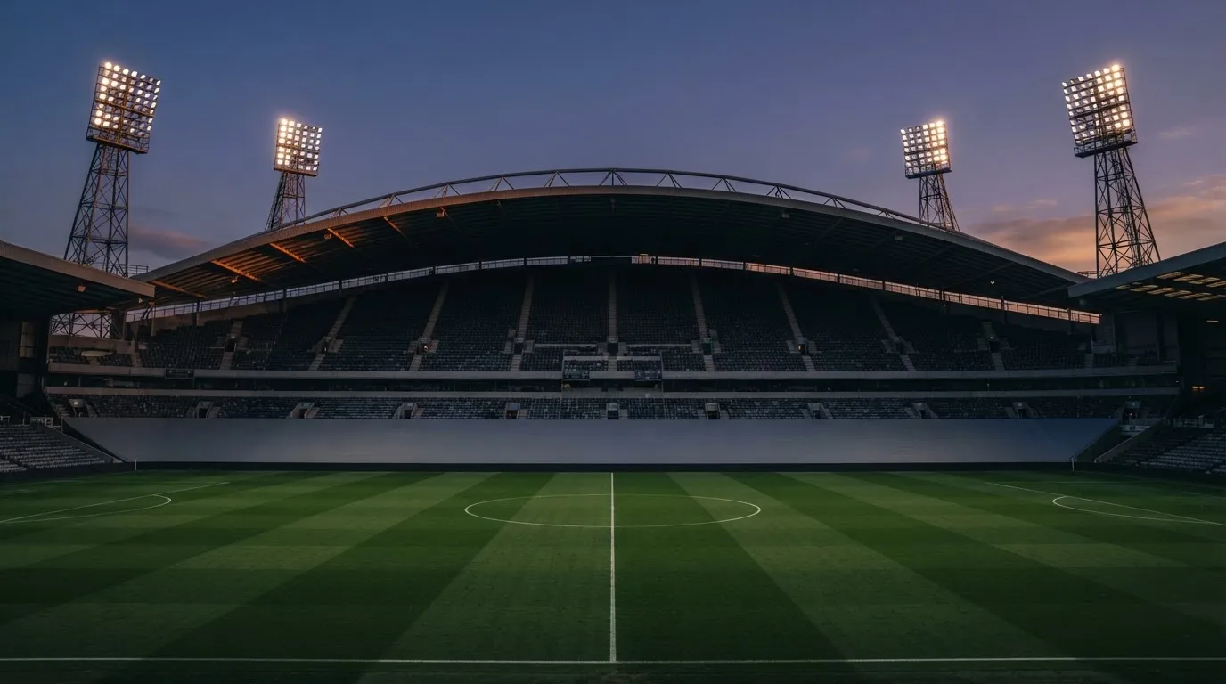 Een leeg voetbalstadion met lichtmasten bij schemering