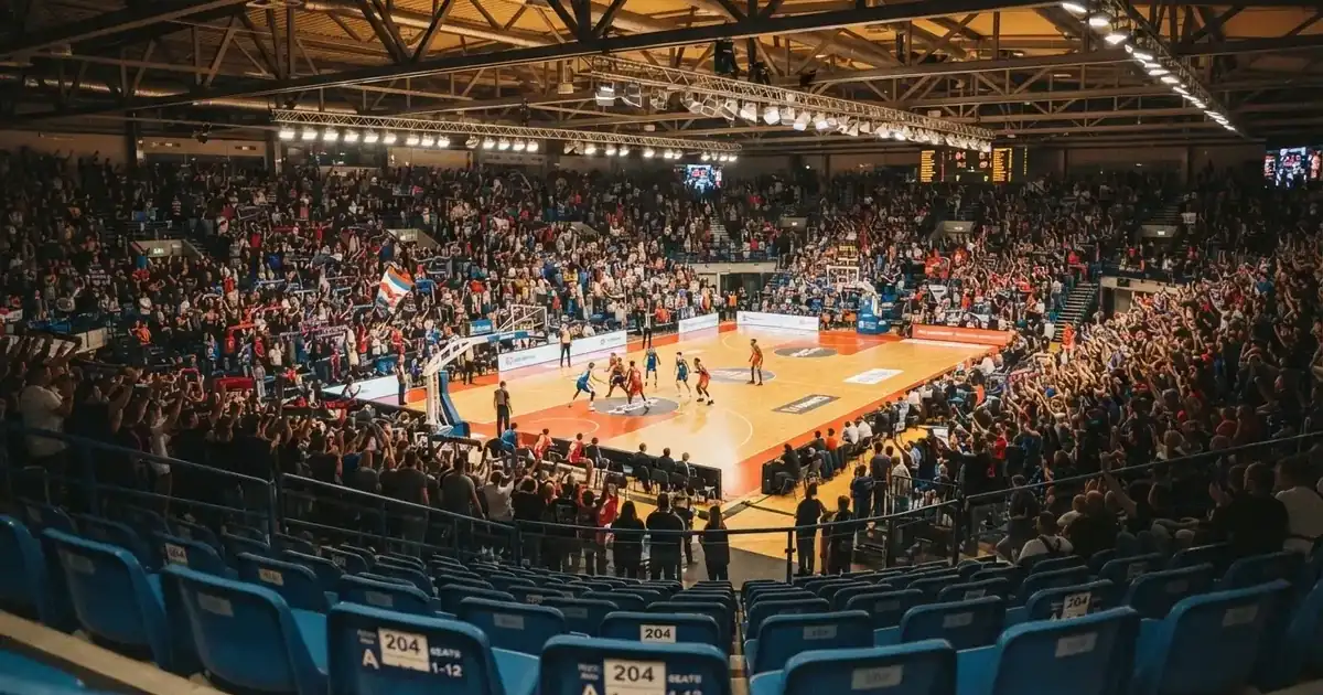 Een volle sporthal onder schijnwerpers, van grote afstand gefotografeerd