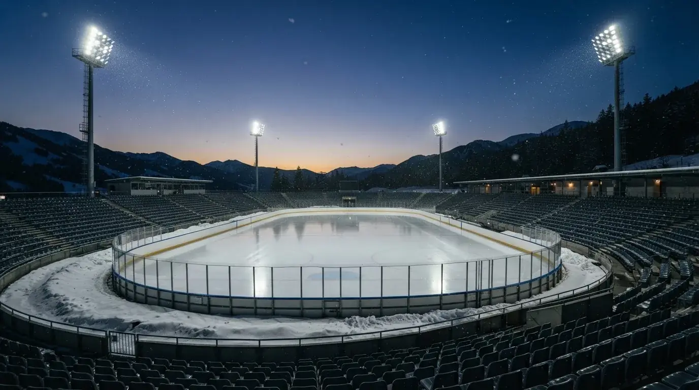 Een leeg voetbalstadion met lichtmasten bij schemering