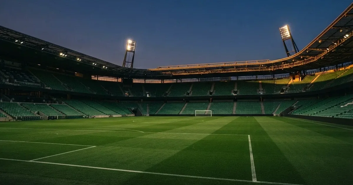 Een leeg voetbalstadion met lichtmasten bij schemering
