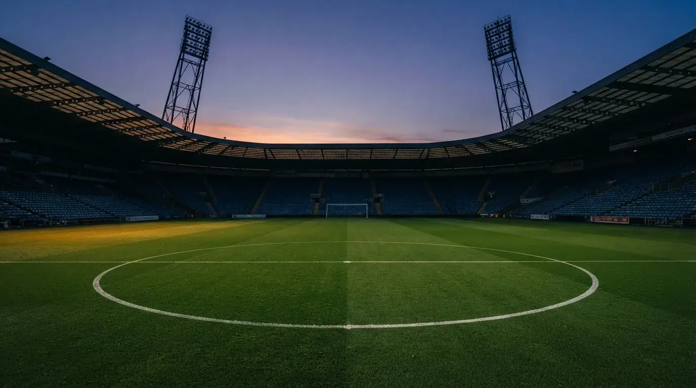 Een leeg voetbalstadion met lichtmasten bij schemering
