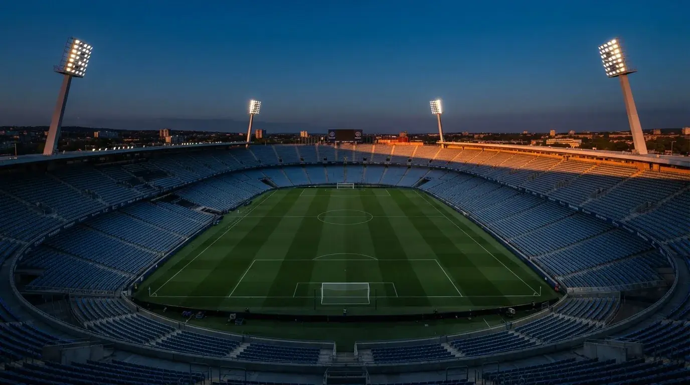 Een leeg voetbalstadion met lichtmasten bij schemering