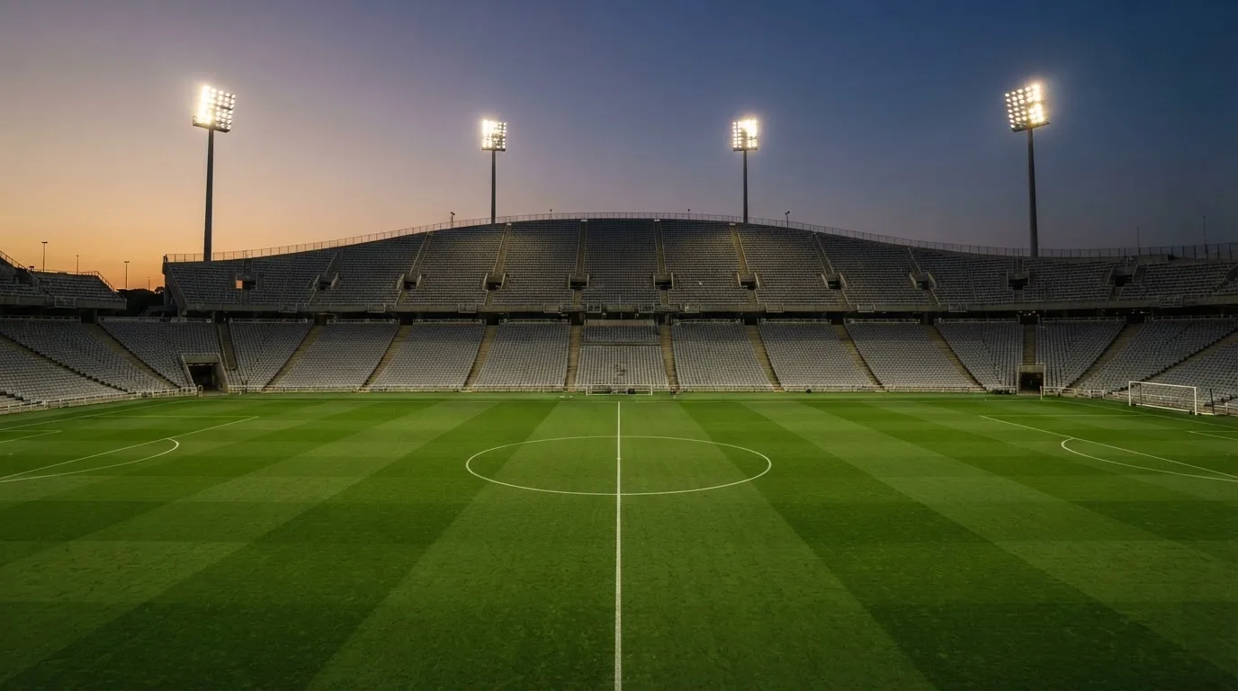 Een leeg voetbalstadion met lichtmasten bij schemering