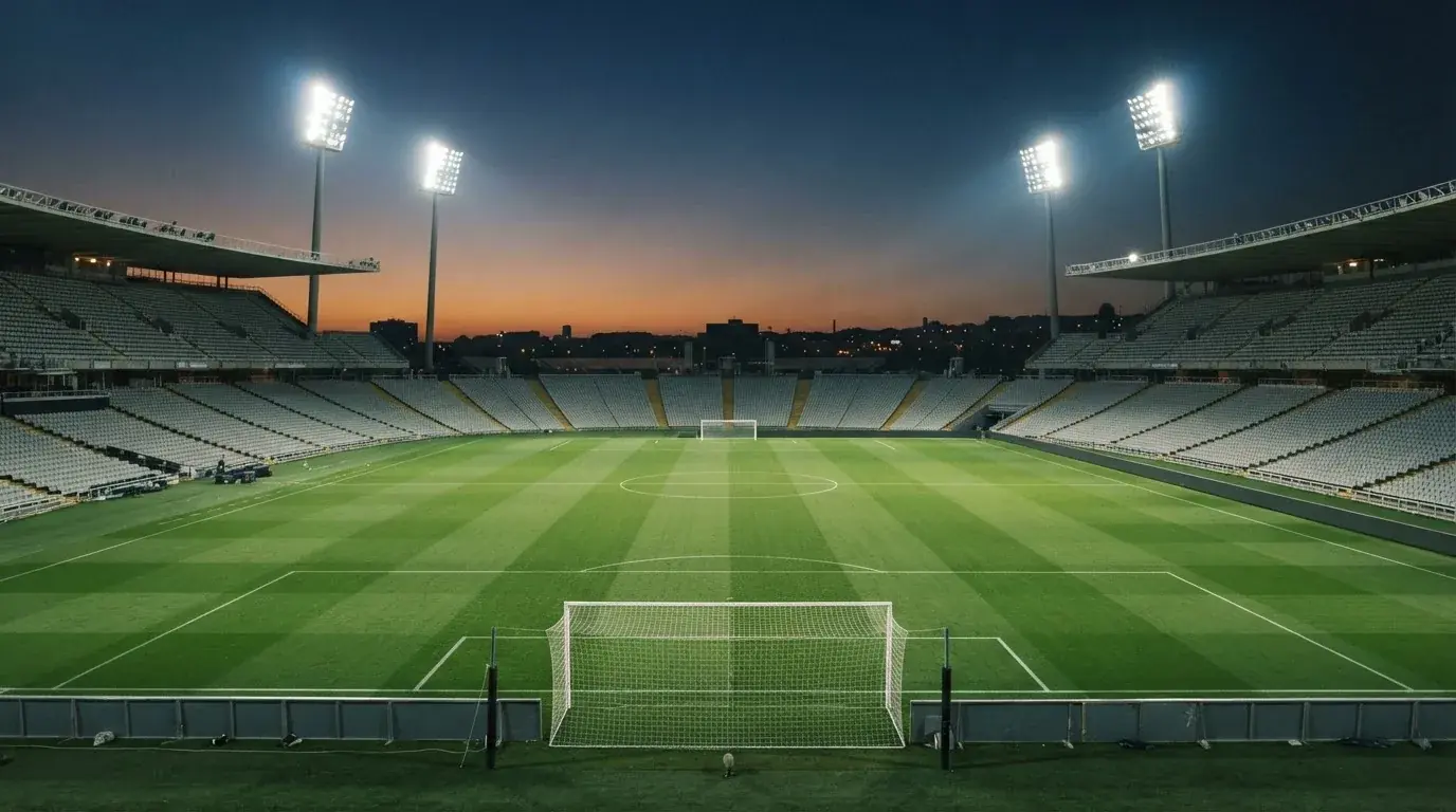 Een leeg voetbalstadion met lichtmasten bij schemering