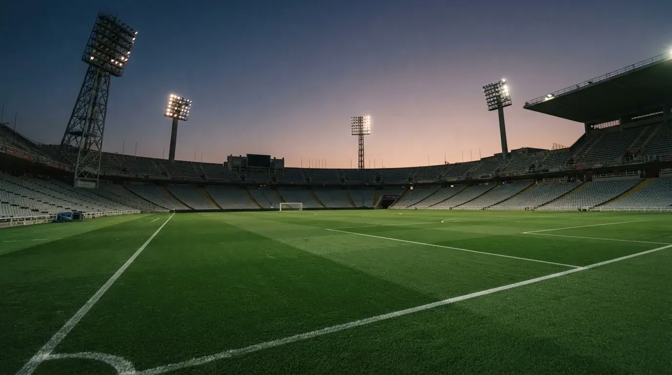 Een leeg voetbalstadion met lichtmasten bij schemering