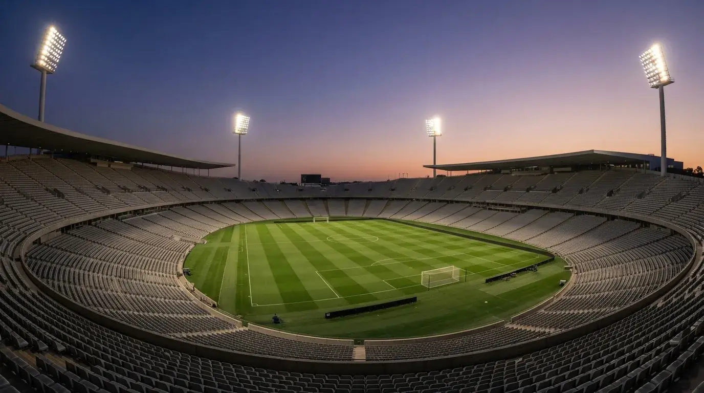 Een leeg voetbalstadion met lichtmasten bij schemering